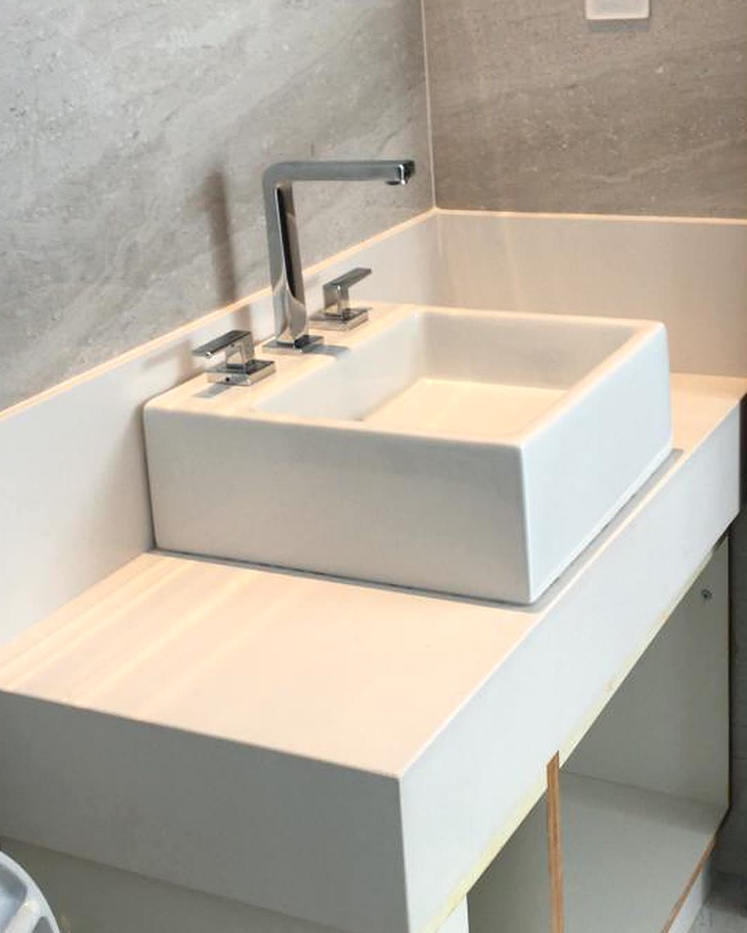 Bancada de lavabo em pedra clara, com rodabanca e cuba de apoio instalada